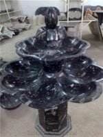 A beautiful black marble fountain from Erfoud, Morocco, adorned with fossilized orthoceras, showcasing the intricate details and natural beauty of the fossils.